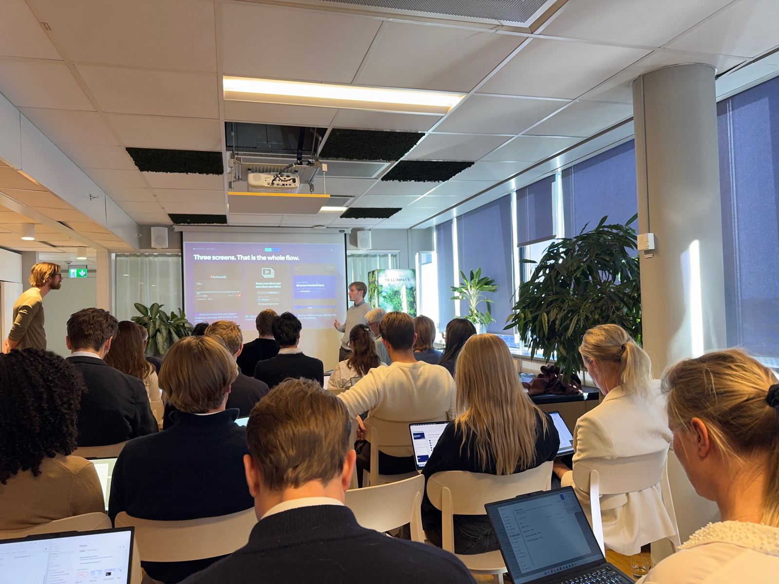 Publik med laptops följer en genomgång av ett AI-arbetsflöde på projektorduk