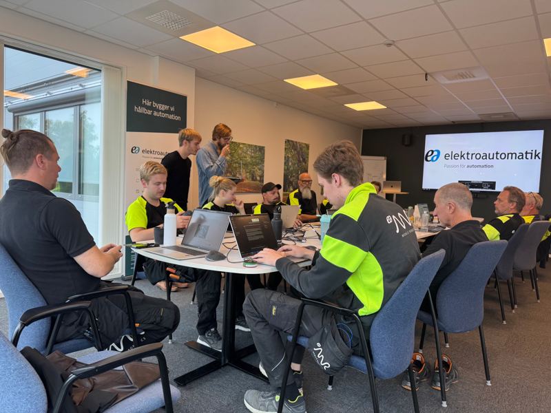 Deltagare arbetar i laptops under en praktisk AI-workshop medan kursledare går runt och hjälper