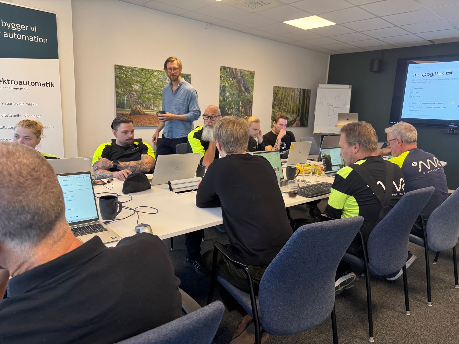 Kursledare visar en övning på skärm medan deltagarna arbetar i egna laptops under en praktisk AI-workshop