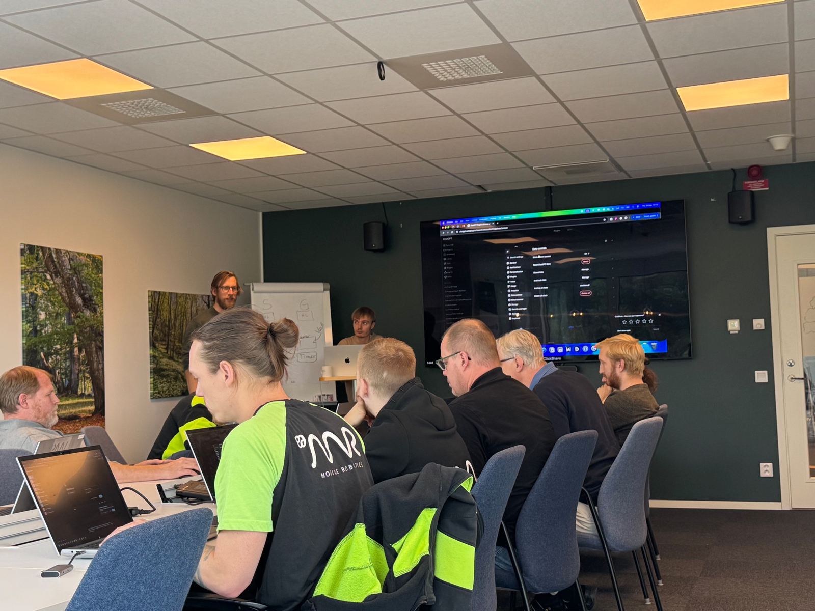 Deltagare med laptops följer en genomgång på storskärm under en teknisk AI-workshop