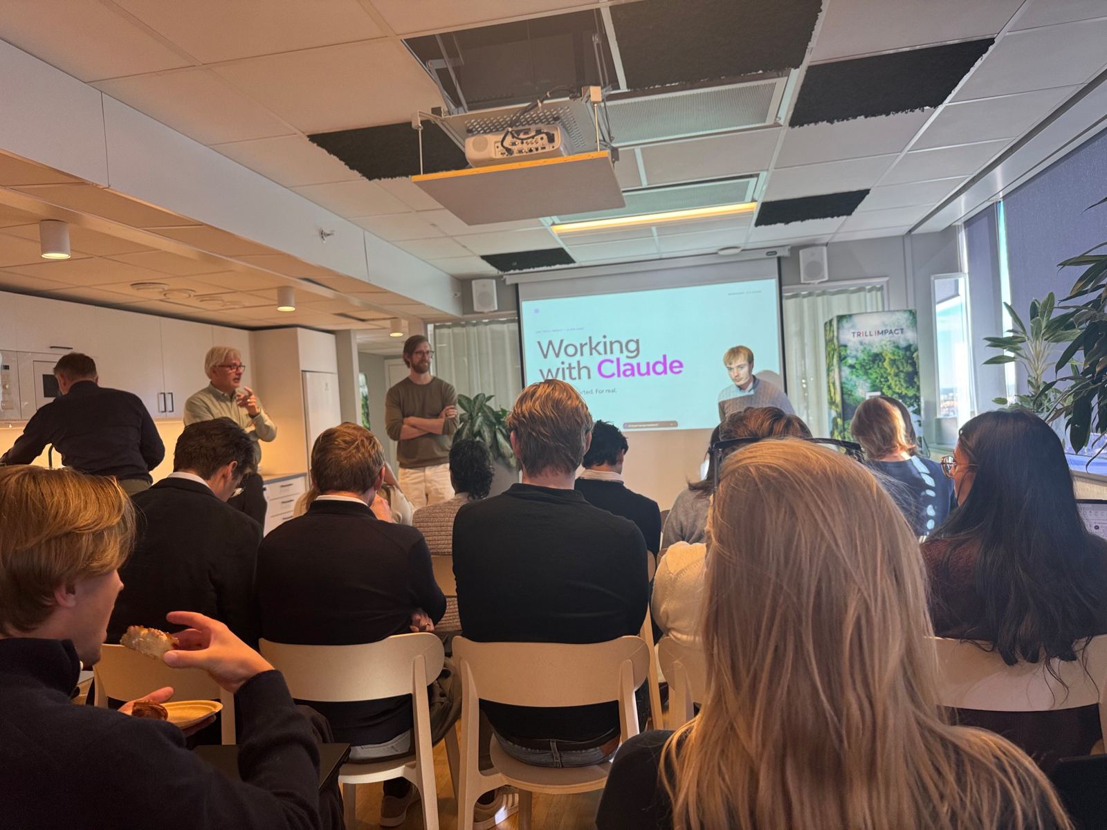 Föreläsning med sliden Working with Claude inför en publik i en konferenslokal