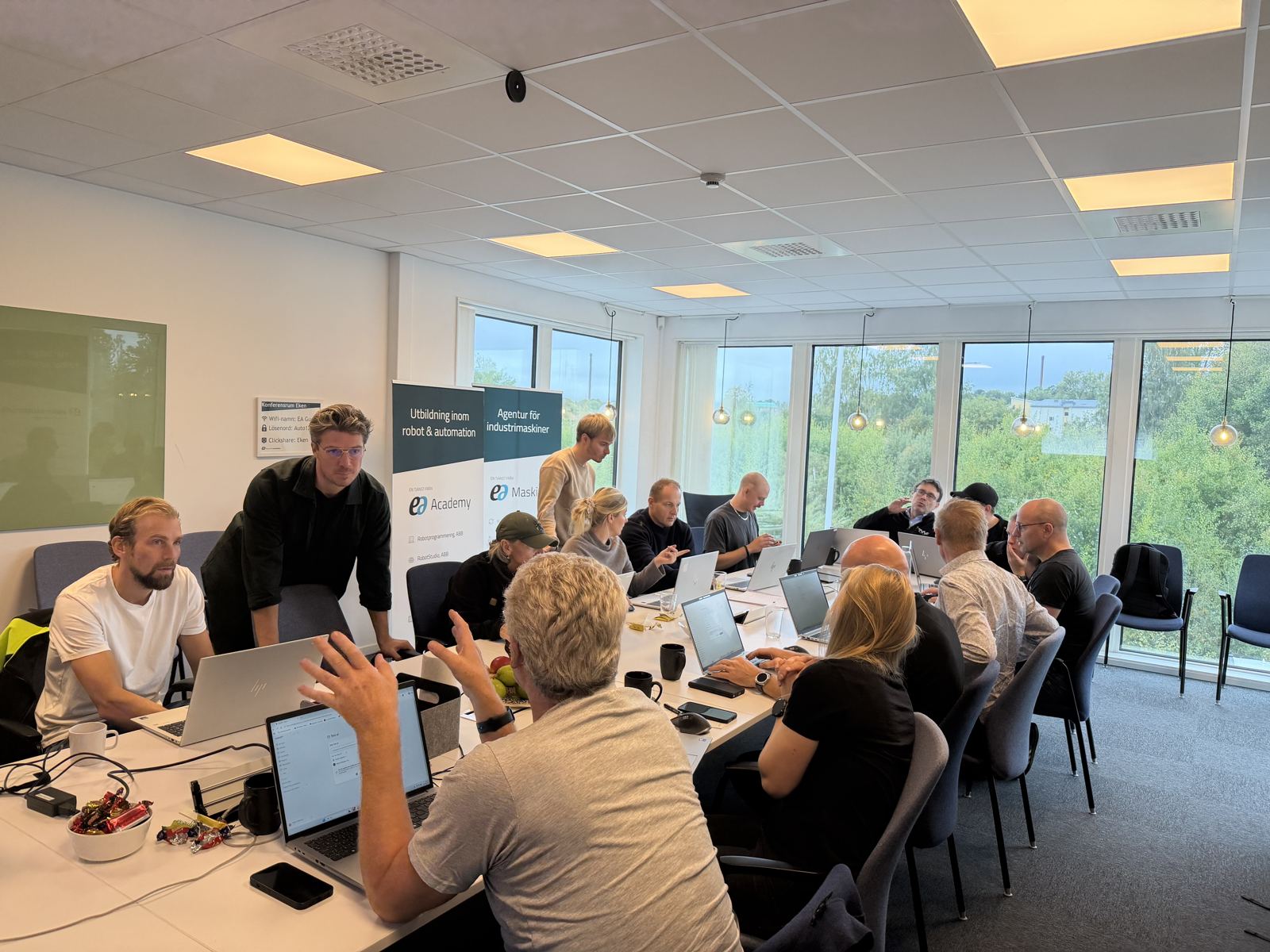 Deltagare från olika roller arbetar i laptops under en praktisk AI-workshop i en ljus lokal